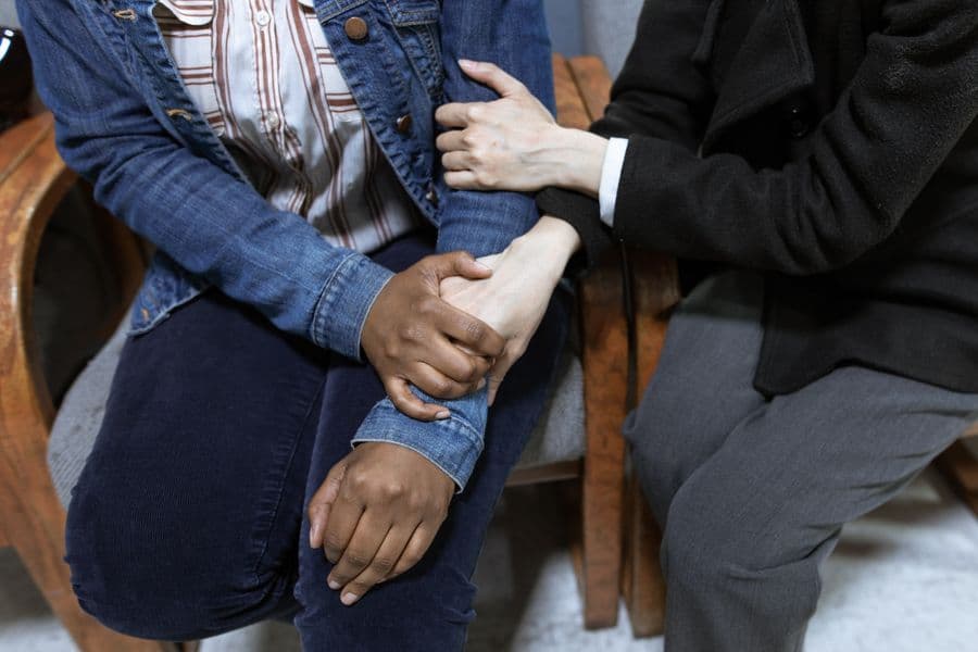 A comforting hand resting on a client's arm during a supportive moment